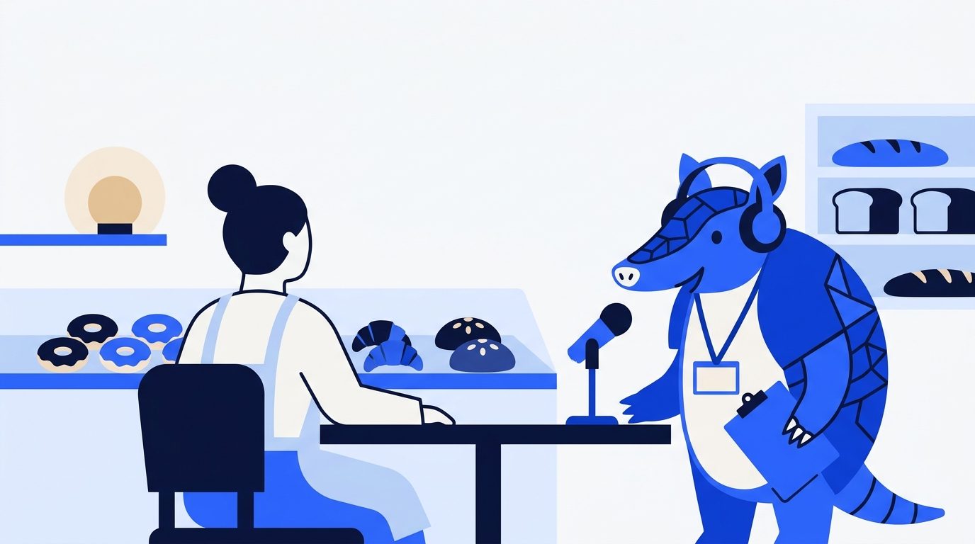 Arlo in headphones interviews a baker across a cafe table with a microphone